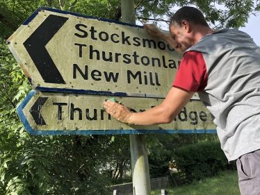 Cllr Richard Smith cleaning road signs in Kirkburton